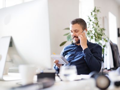 Businessman In Wheelchair At The Desk In His Office.