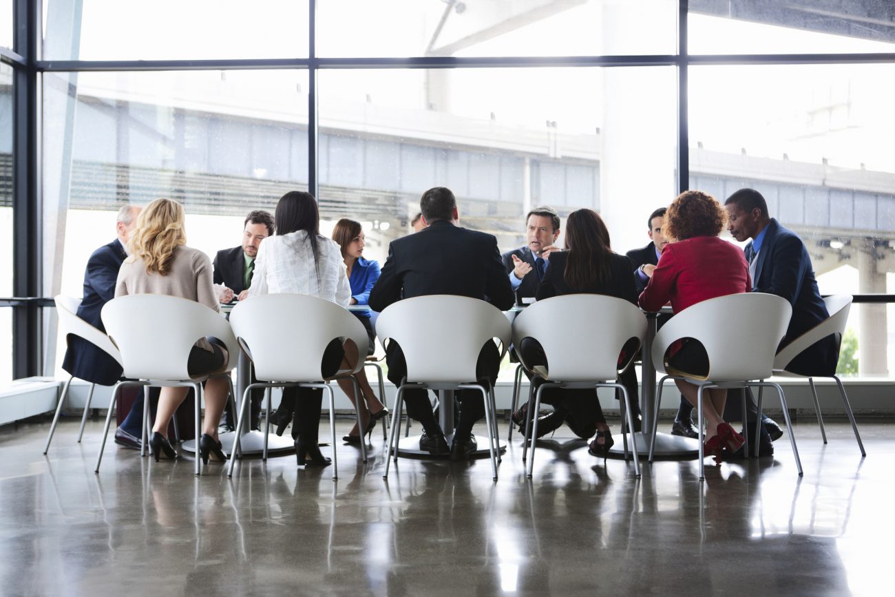 Business Coworkers Meeting At Large Conference Table In Glass Office