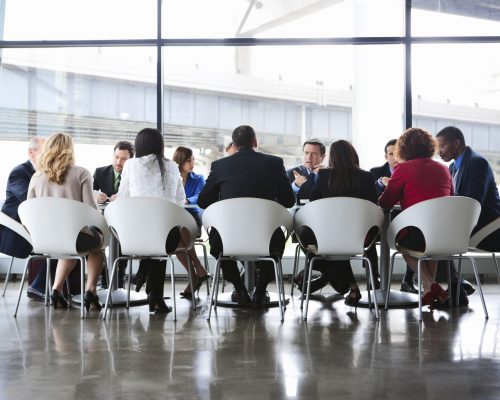 Business Coworkers Meeting At Large Conference Table In Glass Office